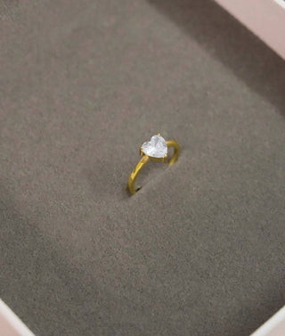 a ring with a heart on it sitting in a box