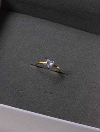 a gold ring with a white diamond in a box