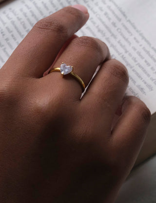 a woman's hand holding a book with a ring on it